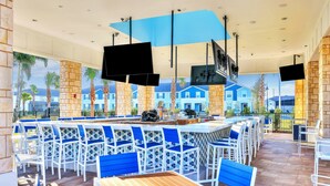 A bar area with white and blue chairs, a long counter, and a view of blue houses in the background. - Inviting Family-friendly Home W/private Pool, Spa, Central AC, & W/D (Davenport)