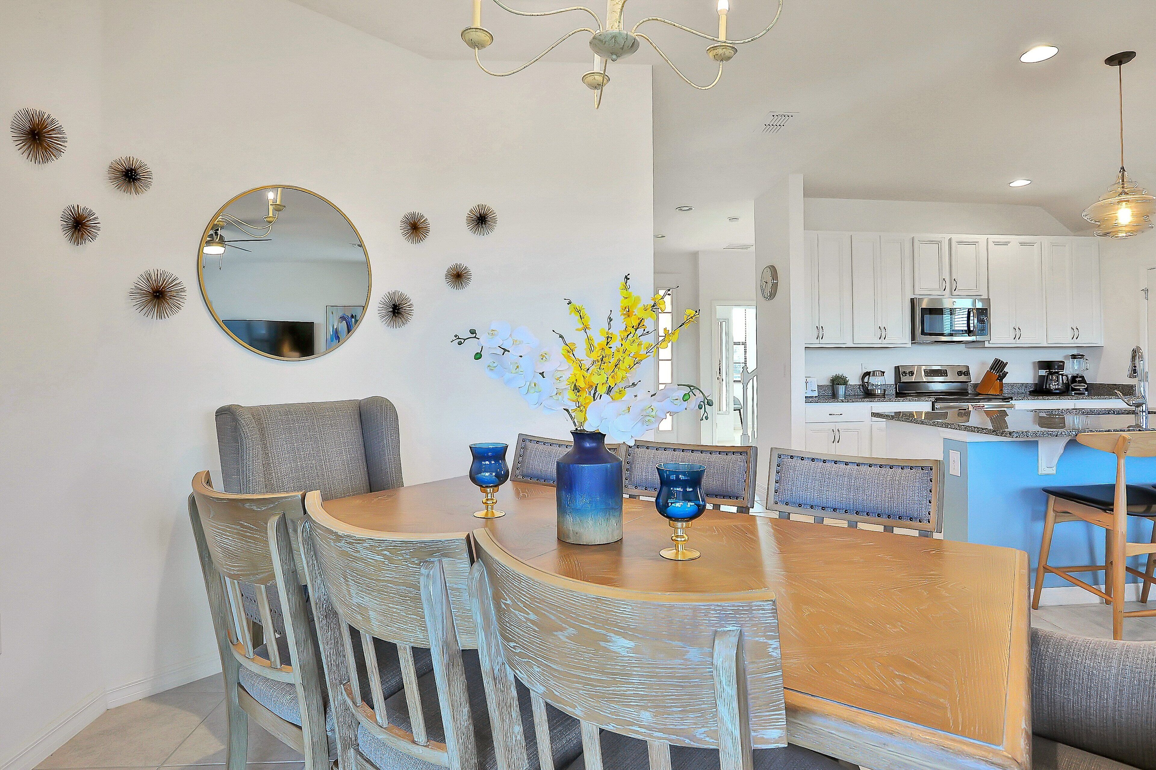 A dining area with a wooden table, wicker chairs, and a vase with flowers.