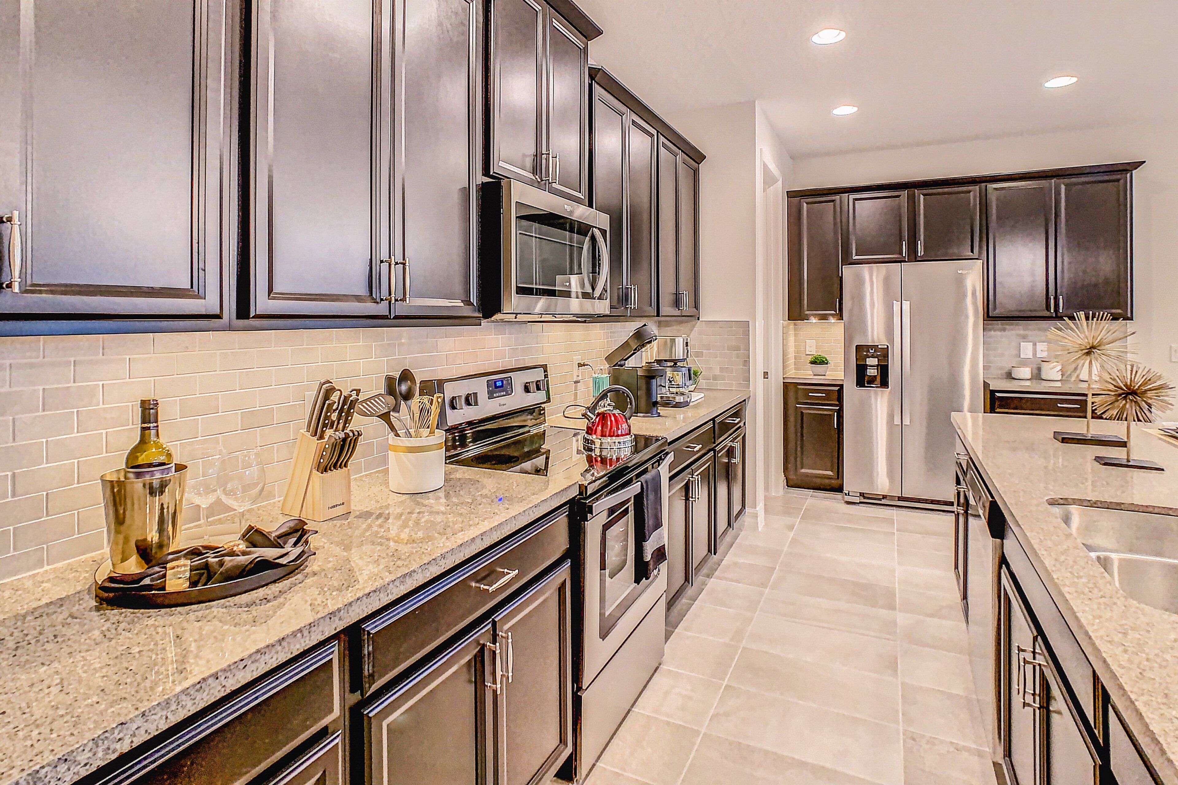 A modern kitchen with stainless steel appliances, dark cabinetry, and a granite countertop.