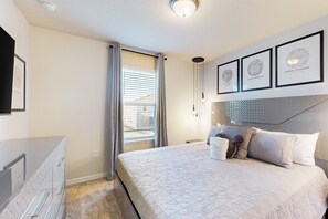 A bedroom with a bed, a dresser, a window with curtains, and framed pictures on the wall. - Luxury Home With Themed Bedrooms,arcade Games and Private Pool (Clermont)