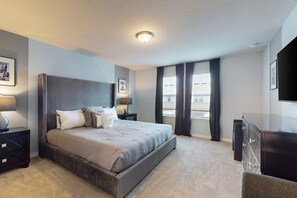 A modern bedroom with a large bed, bedside tables, a dresser, and a flat-screen TV. - Luxury Home With Themed Bedrooms,arcade Games and Private Pool (Clermont)