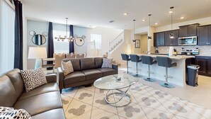 A modern living room with a brown leather sofa, a glass coffee table, and a patterned rug. - Luxury Home With Themed Bedrooms,arcade Games and Private Pool (Clermont)