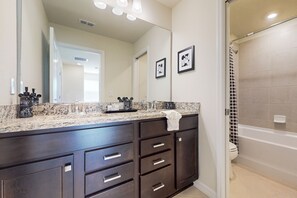 A bathroom with dark wooden cabinets, a granite countertop, a large mirror, and a shower with a black and white polka dot curtain. - Luxury Home With Themed Bedrooms,arcade Games and Private Pool (Clermont)