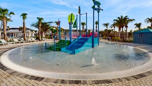 A water play area with slides and a pool, surrounded by palm trees and lounge chairs. - Luxury Home With Themed Bedrooms,arcade Games and Private Pool (Clermont)
