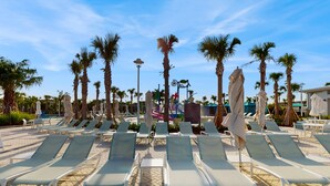 A poolside area with lounge chairs, palm trees, and umbrellas. - Luxury Home With Themed Bedrooms,arcade Games and Private Pool (Clermont)