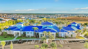 A large building with a blue roof, surrounded by parking and palm trees. - New Home With Private Pool/spa & Resort Waterpark/arcade Access (Davenport)