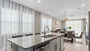 A modern kitchen with granite countertops, stainless steel appliances, and a central island with a sink. - Dog-friendly Getaway With Private Pool + Spa, Putting Green, Patio, & Game Room (Kissimmee)