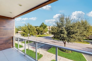 A balcony with a view of a street, trees, and a building in the background. - Spacious Modern Townhouse With Resort Pool Access and Elegant Open Living Spaces (Kissimmee)
