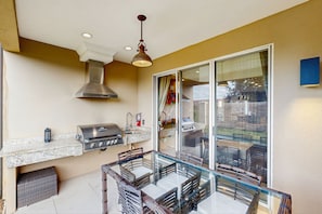 A kitchen with a gas stove, overhead ventilation, and a glass dining table. - Spacious Modern Townhouse With Resort Pool Access and Elegant Open Living Spaces (Kissimmee)