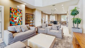 Un salon spacieux avec un grand canapé d’angle, une table basse et un tableau abstrait aux couleurs vives accroché au mur.