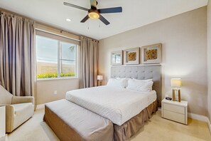 A bedroom with a bed, bedside tables, a ceiling fan, and a window with curtains. - Spacious Modern Townhouse With Resort Pool Access and Elegant Open Living Spaces (Kissimmee)