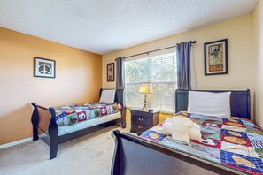 Een slaapkamer met twee bedden, een nachtkastje, een lamp en een raam met gordijnen.
