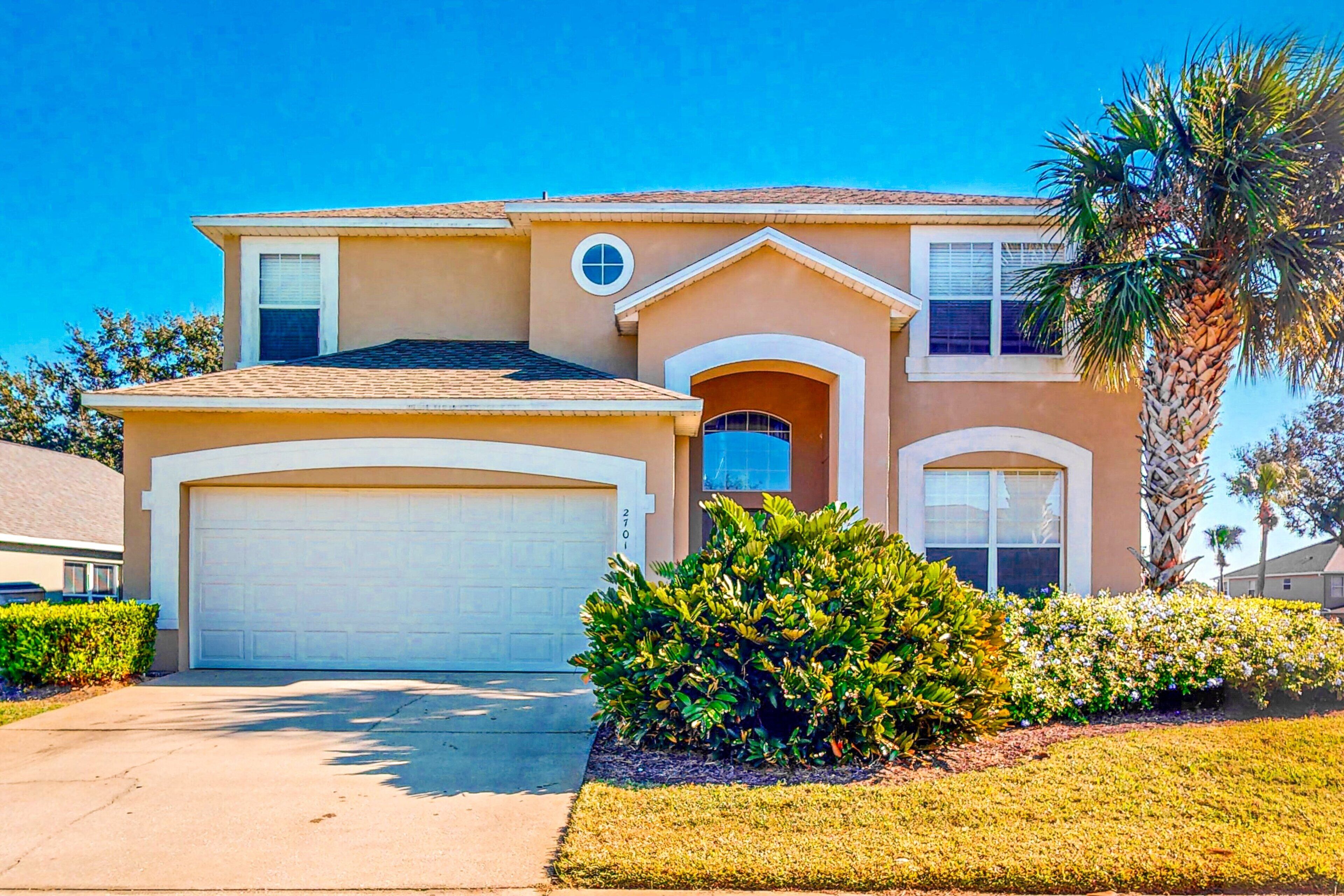 A two-story house with a garage, a covered entryway, and a well-maintained lawn.
