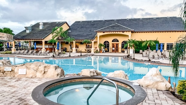 A pool area with lounge chairs, a hot tub, and a building with outdoor seating. - Dog-friendly Home With Private Pool, High-speed Wifi, Central AC, & Washer/dryer (Kissimmee)