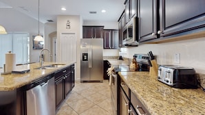 A modern kitchen with stainless steel appliances, granite countertops, and dark cabinetry. - Dog-friendly Home With Private Pool, High-speed Wifi, Central AC, & Washer/dryer (Kissimmee)