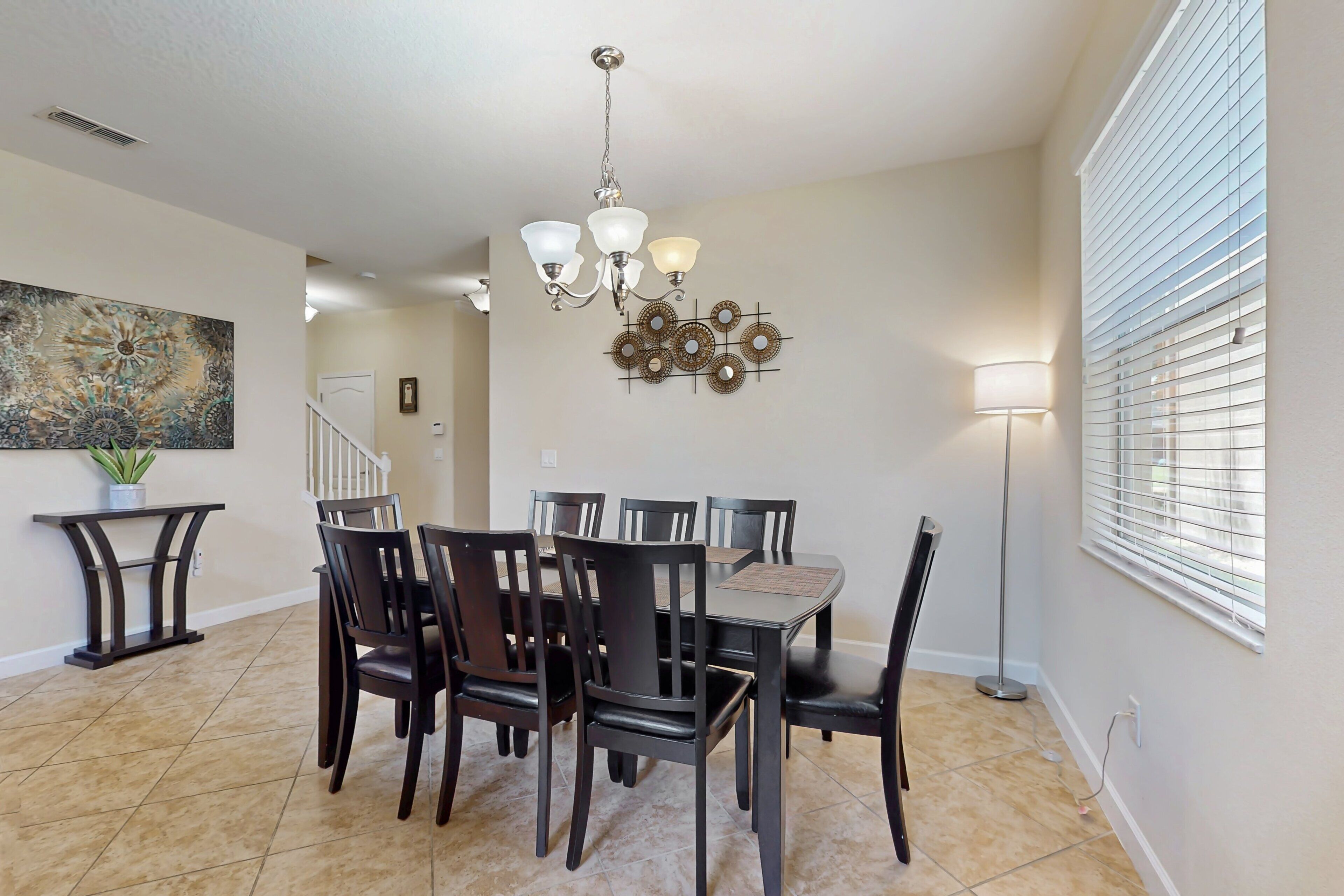A dining area with a chandelier, a wall-mounted decorative piece, and a lamp.