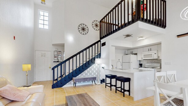 A spacious living area with a staircase, a kitchen, and a dining area. - Ideally Located Modern Townhome With Open Layout & Pool - Snowbird-friendly (Kissimmee)