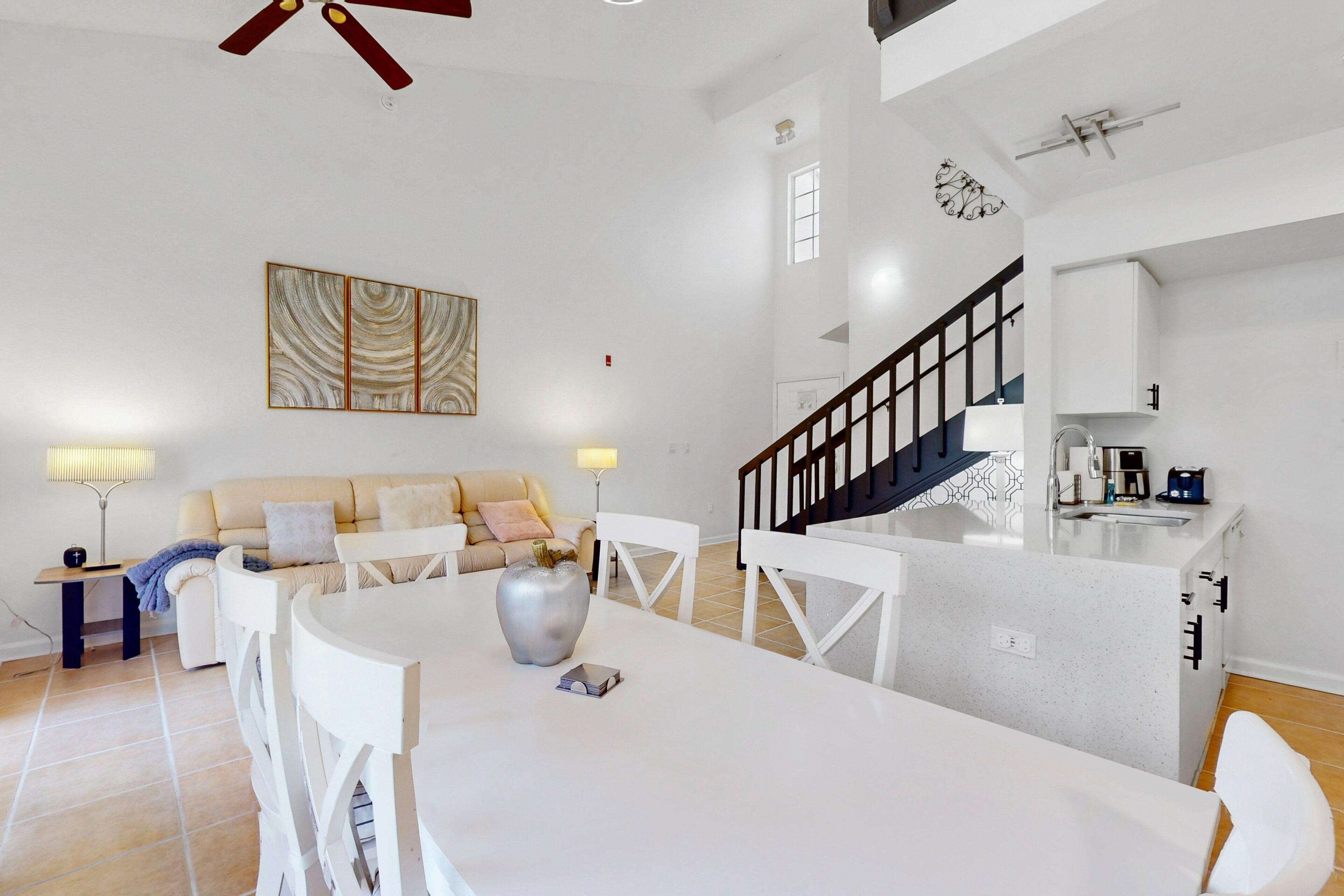 A modern living space with a dining area, kitchen, and staircase.