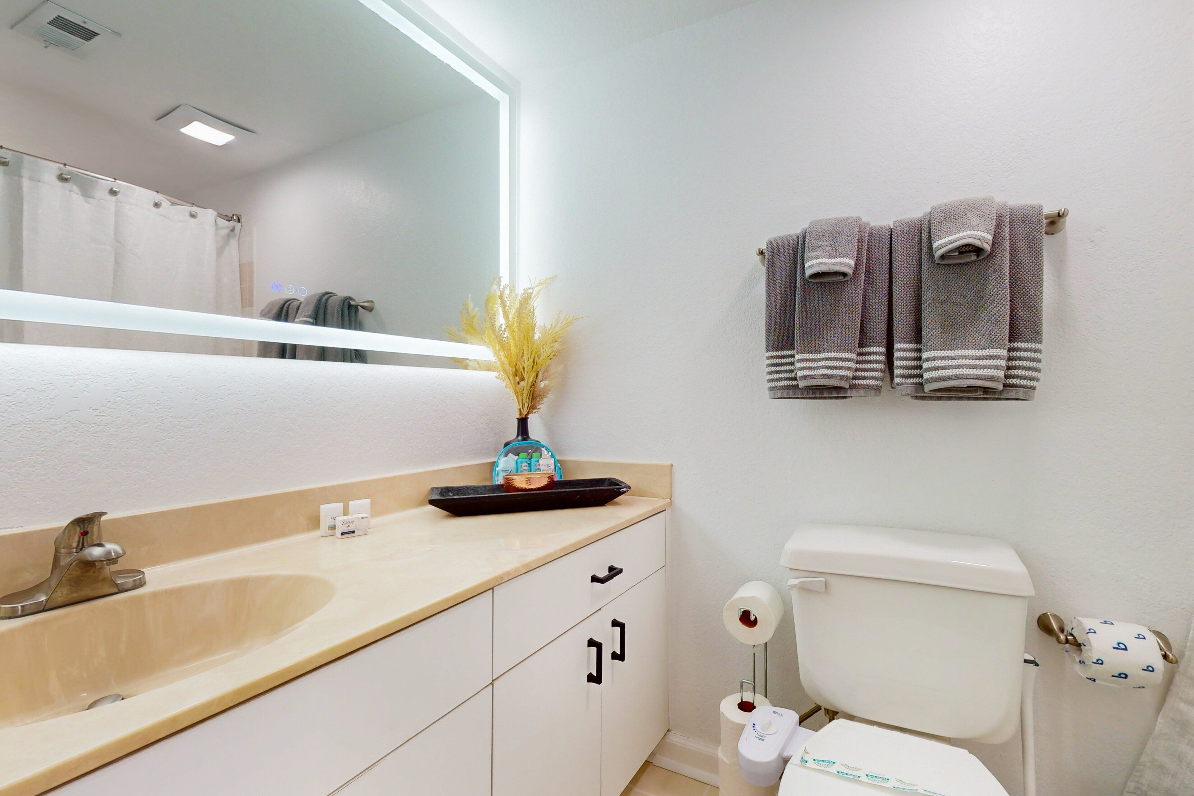A bathroom with a sink, mirror, toilet, and towels.