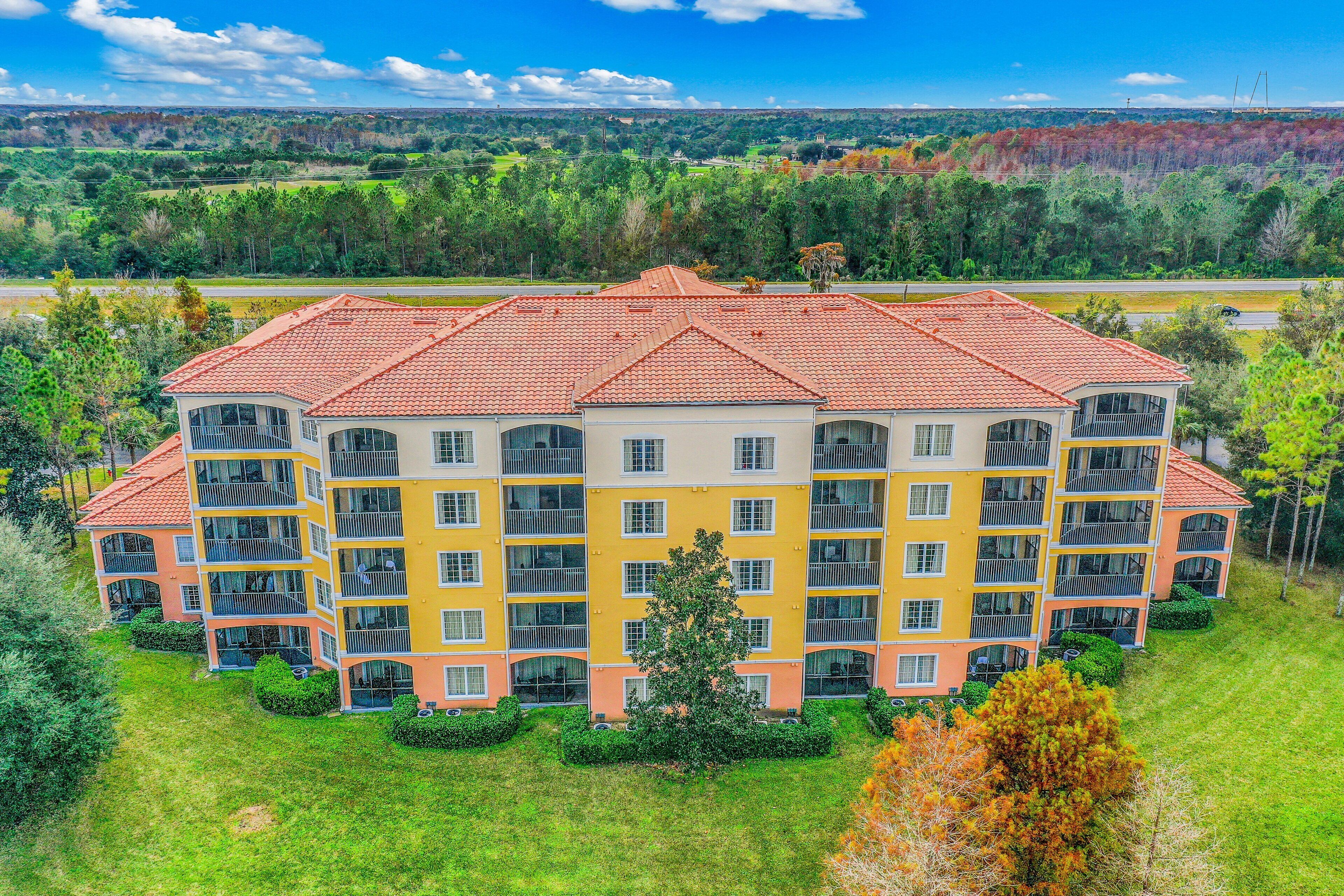 Ein mehrstöckiges Hotel mit Balkonen, umgeben von viel Grün und freiem Blick auf die Landschaft.