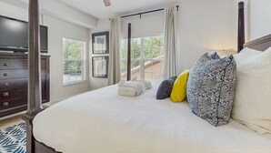 A bedroom with a bed, a ceiling fan, a TV, a dresser, and a window with blinds. - Dog-friendly Condo With Gym, Wifi, Balcony - Close to Theme Parks (Orlando)