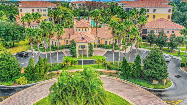 A multi-story hotel with a central courtyard, palm trees, and a parking area. - Dog-friendly Condo With Gym, Wifi, Balcony - Close to Theme Parks (Orlando)