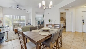 A spacious dining area with a wooden table, chairs, and a chandelier. - Dog-friendly Condo With Gym, Wifi, Balcony - Close to Theme Parks (Orlando)
