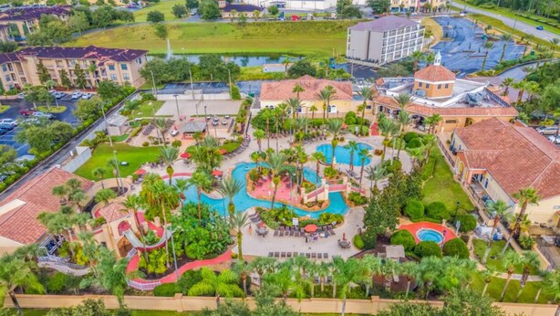 Eine Luftaufnahme eines Resorts mit mehreren Schwimmbecken, Palmen und einem zentralen Gebäude mit einer Kuppel.