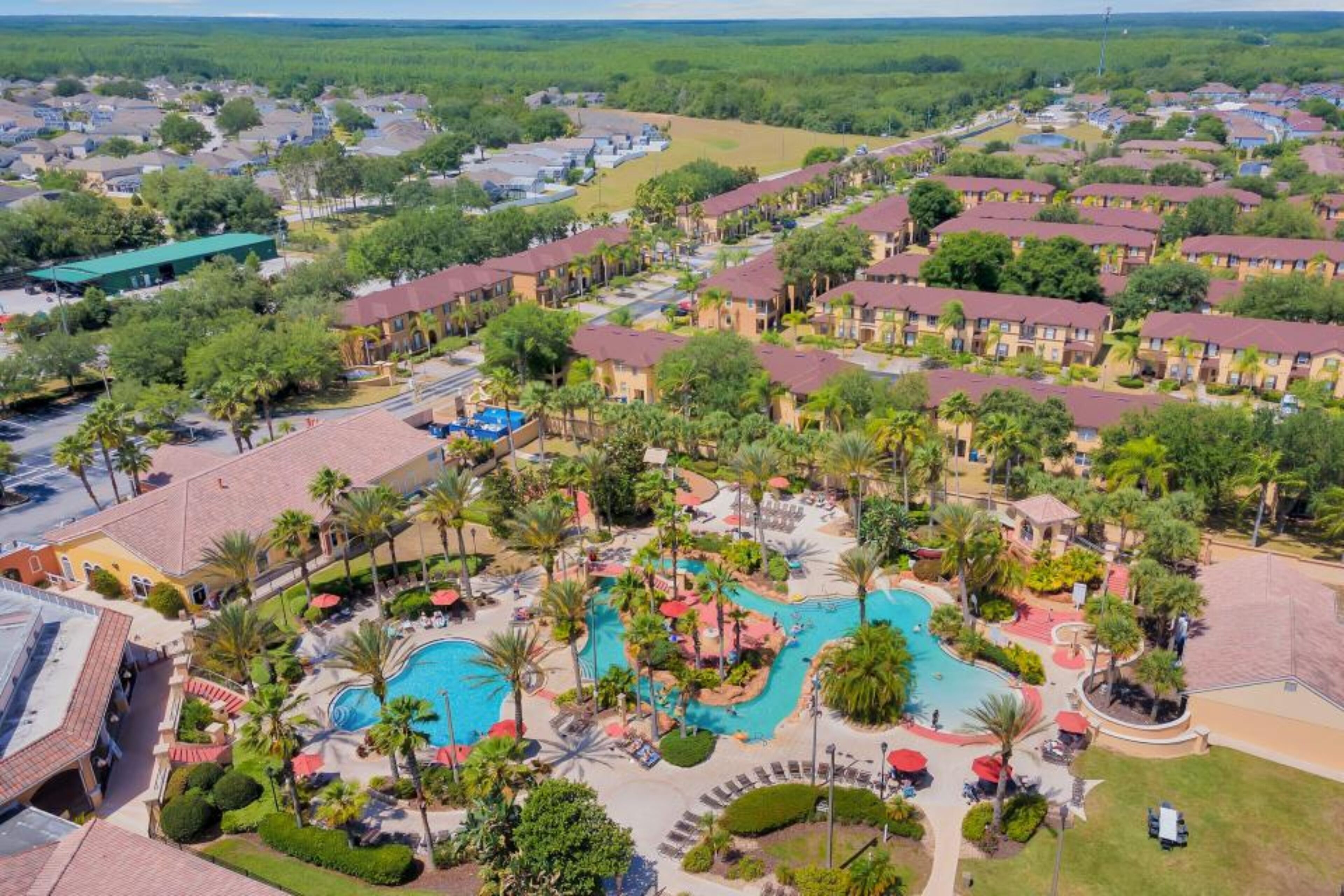 Un resort con diversi edifici, una piscina centrale e vegetazione circostante.