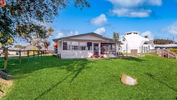 A house with a covered porch, a fenced yard, and a large tree.