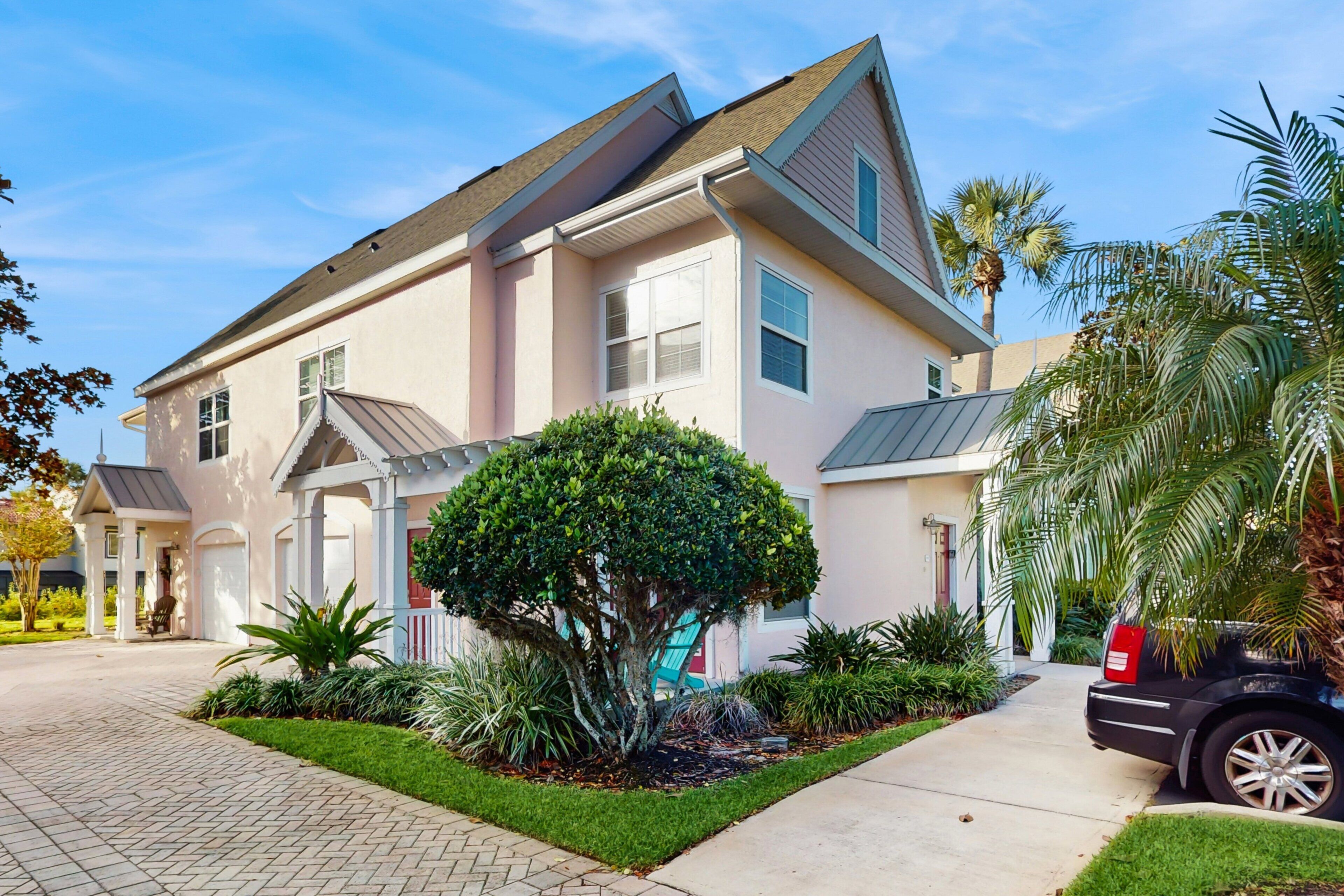 A two-story house with a paved driveway, a well-maintained lawn, and a variety of plants.