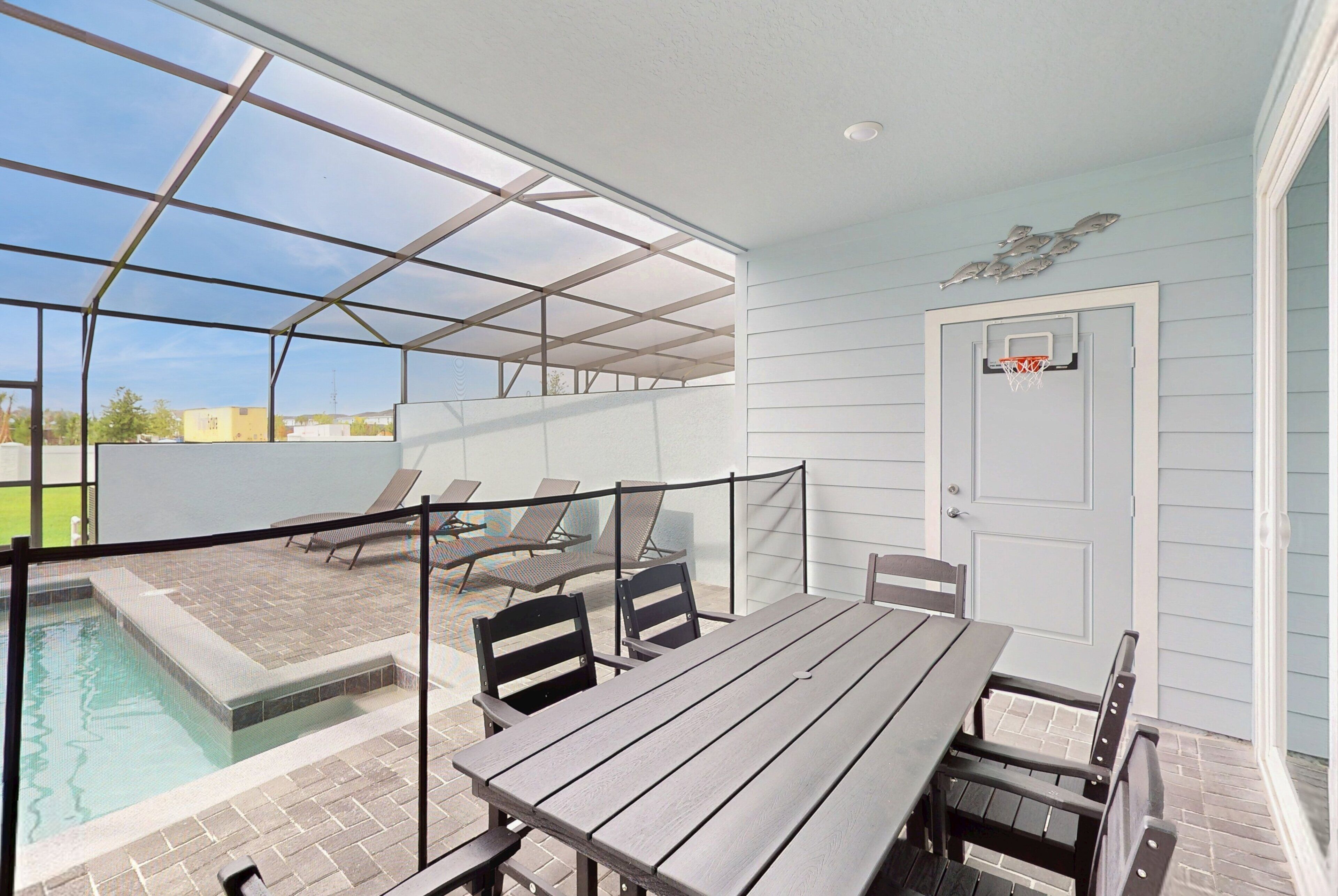 Un patio cubierto con piscina, mobiliario exterior y una puerta con aro de baloncesto.