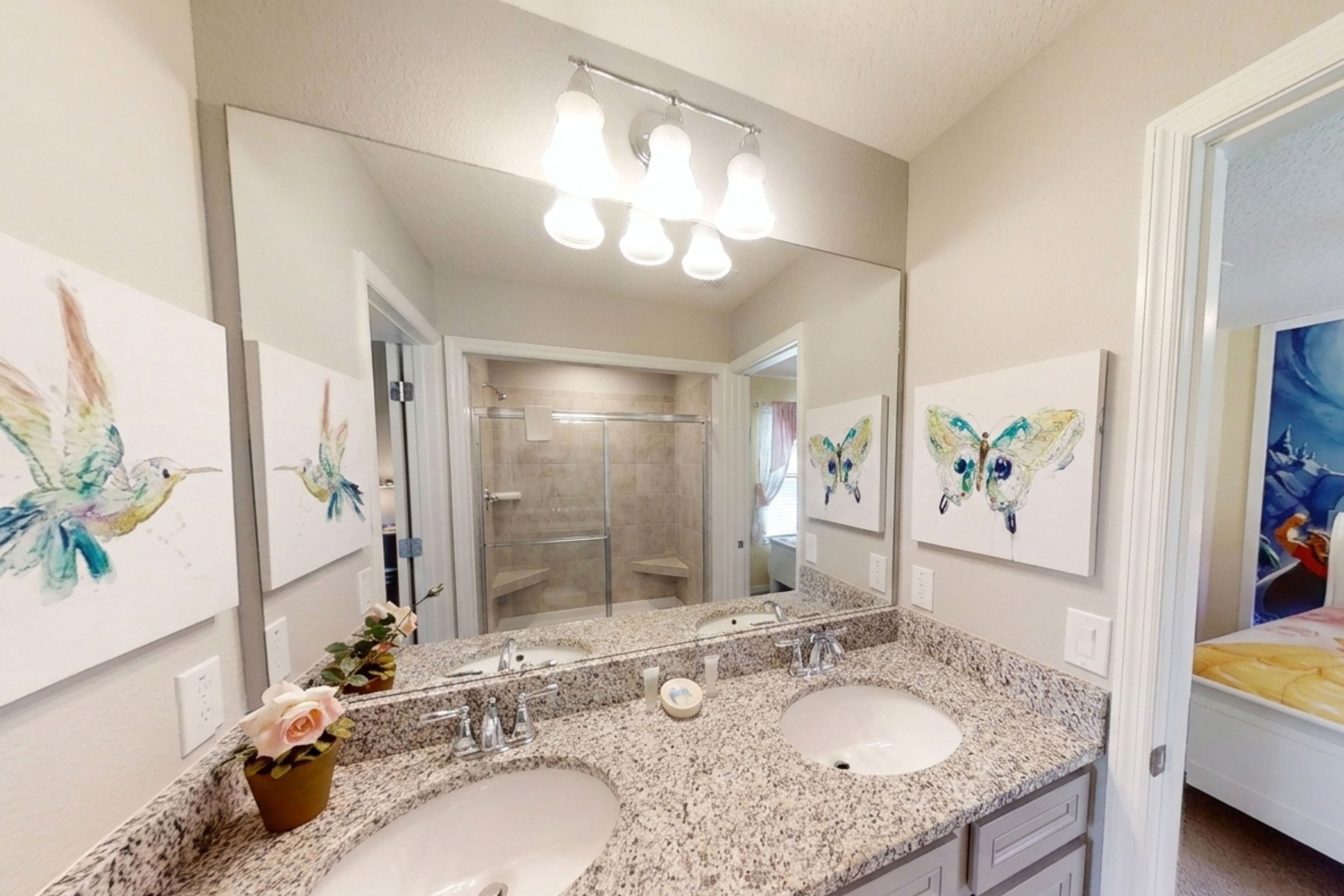 A bathroom with two sinks, a large mirror, and butterfly artwork on the walls.