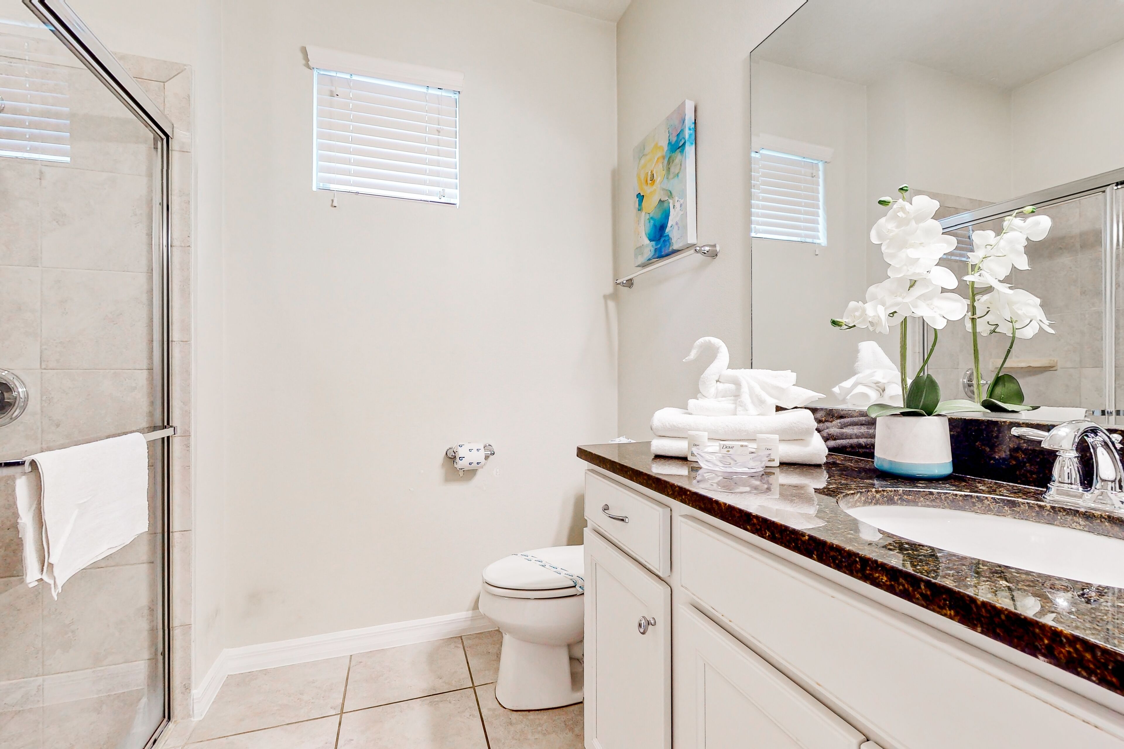 Une salle de bain équipée d’une douche, de toilettes, d’un lavabo et d’un miroir.