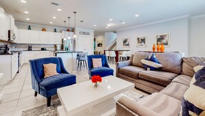A modern living room with a white coffee table, blue armchairs, and a brown sofa. - Spacious Home w/ Private Pool, Wifi, Central AC, Private Washer/dryer (Kissimmee)
