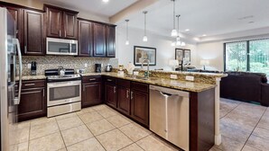 A modern kitchen with dark wood cabinets, stainless steel appliances, and a granite countertop. - Charming Dog-friendly Home With Pool, hot Tub, Fitness Center, Patio, & Kitchen (Davenport)