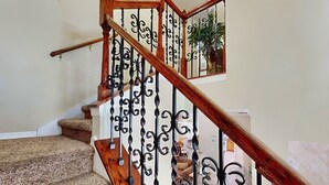 Eine Treppe mit hölzernem Geländer und schwarzen schmiedeeisernen Spindeln.