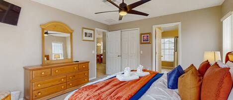 A bedroom with a bed, a dresser, a ceiling fan, and a large mirror.