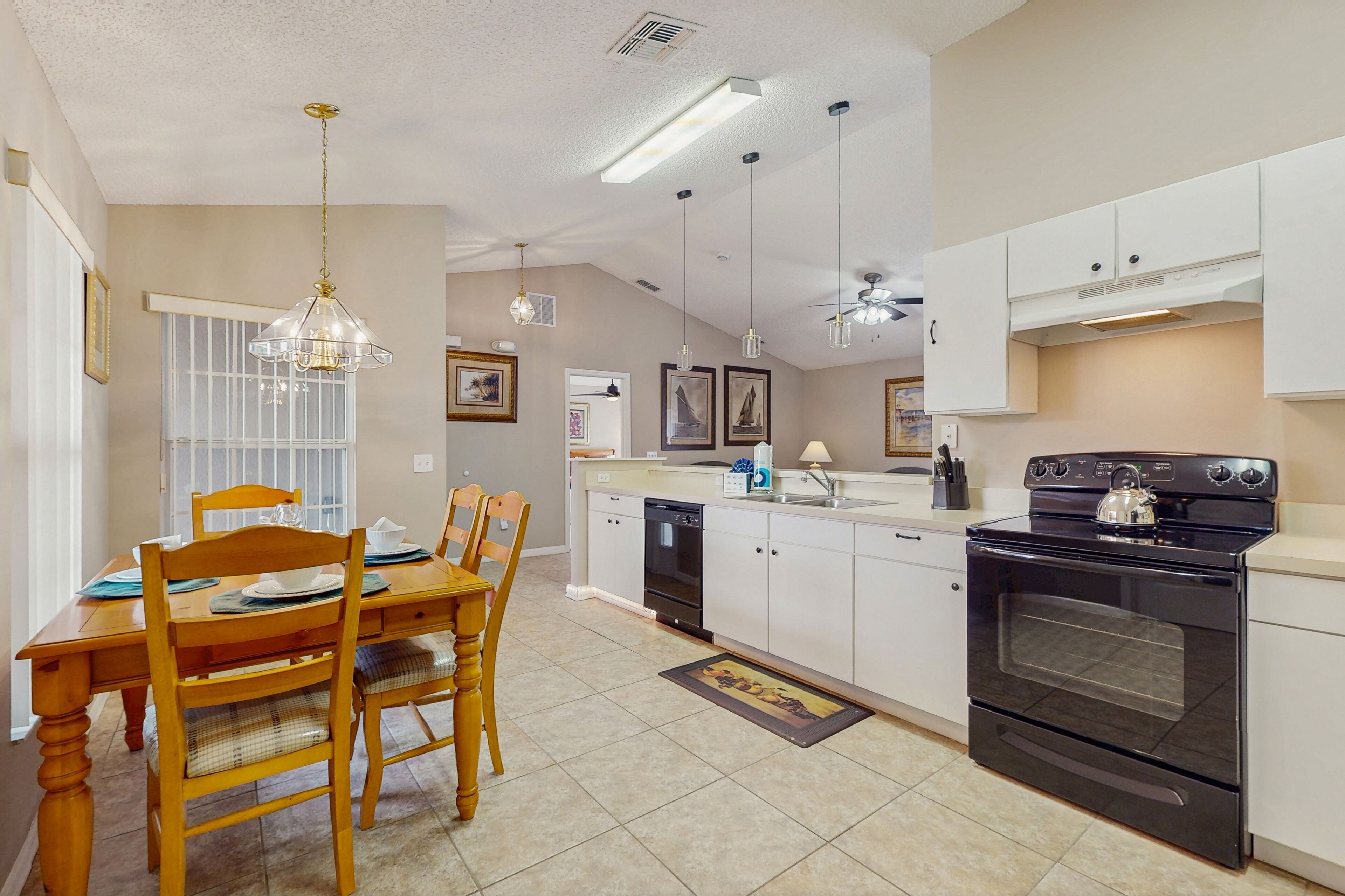 A kitchen with a black stove, white cabinets, and a dining area with wooden chairs and a table.