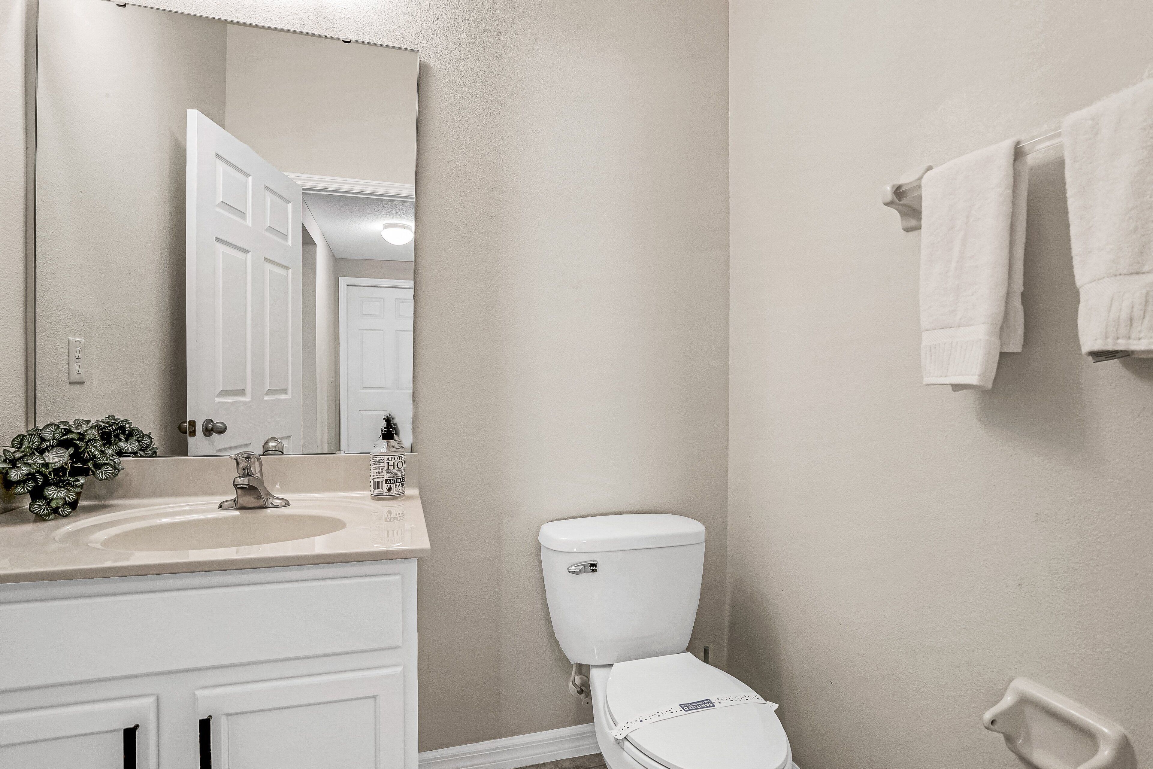 A bathroom with a white sink, a toilet, a mirror, and a towel rack.