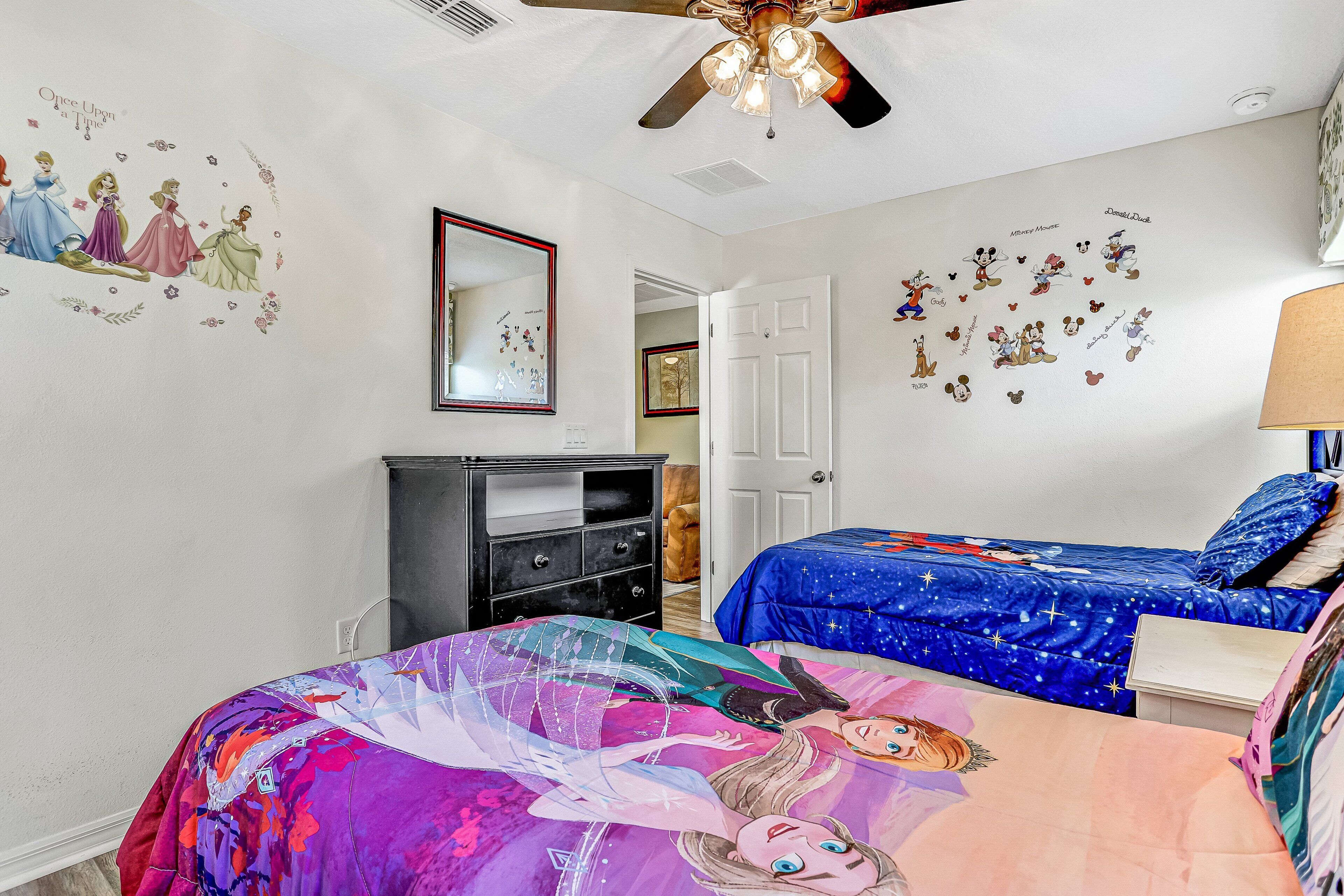 A bedroom with a bed, dresser, and a ceiling fan.