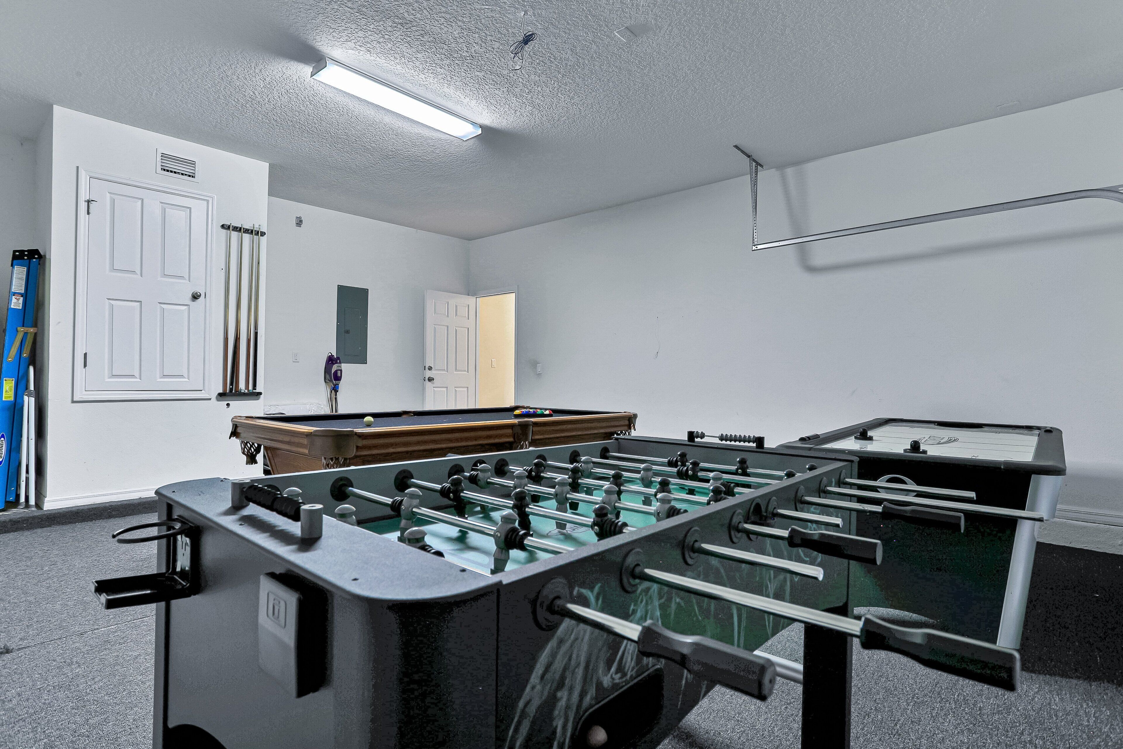 Una habitación con mesa de futbolín, mesa de billar y una puerta.