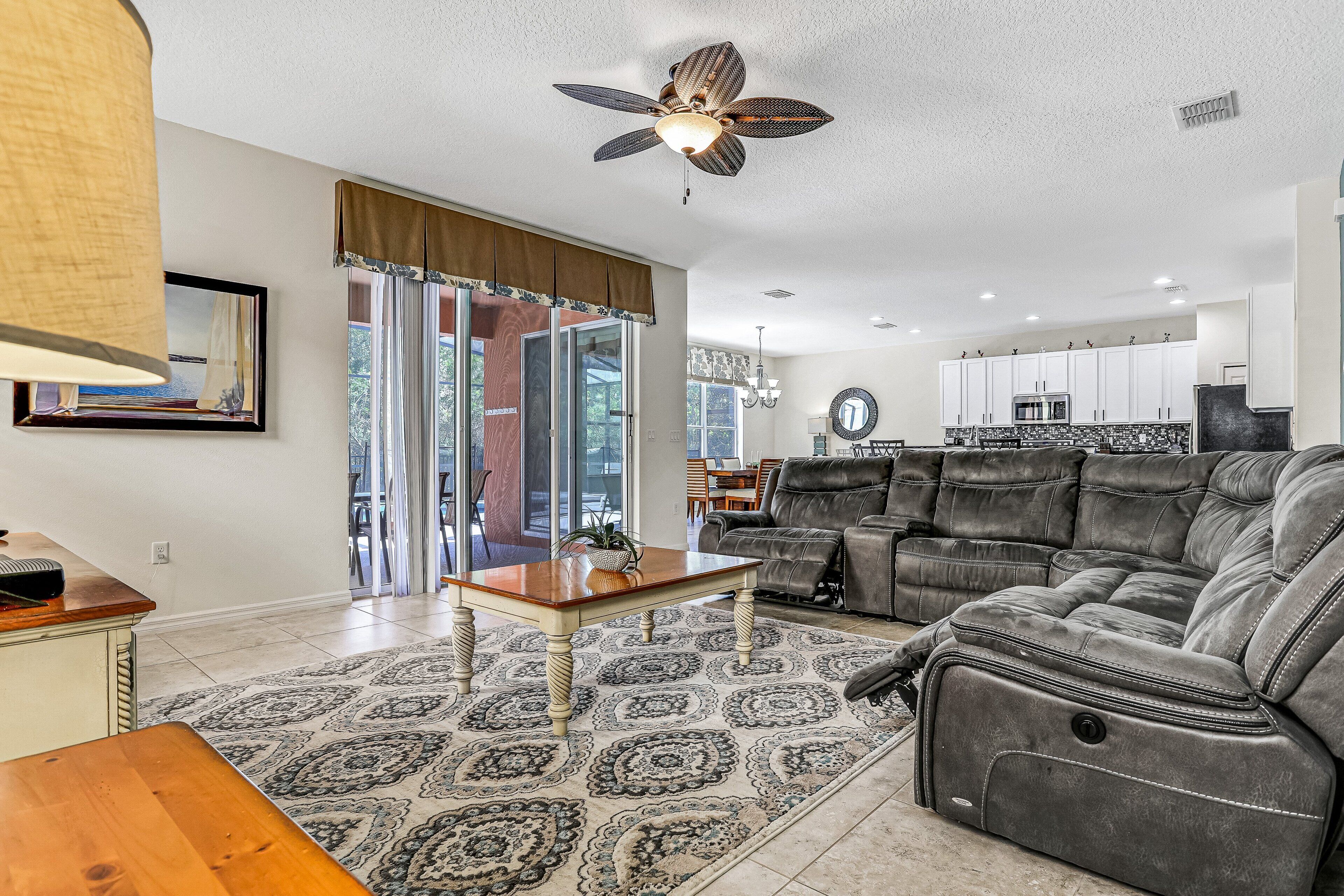 A living room with a ceiling fan, a sofa, a coffee table, and a rug.