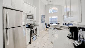 A modern kitchen with white cabinets, stainless steel appliances, a large window, and a coffee maker. - Beautiful Home With Private Pool, Screened Lanai, Wifi, Private W/d, and AC (Kissimmee)
