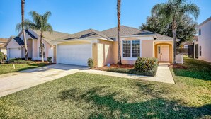 A residential house with a garage, a well-maintained lawn, and palm trees. - Beautiful Home With Private Pool, Screened Lanai, Wifi, Private W/d, and AC (Kissimmee)