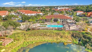 A residential area with a swimming pool, a water feature, and red-roofed houses.