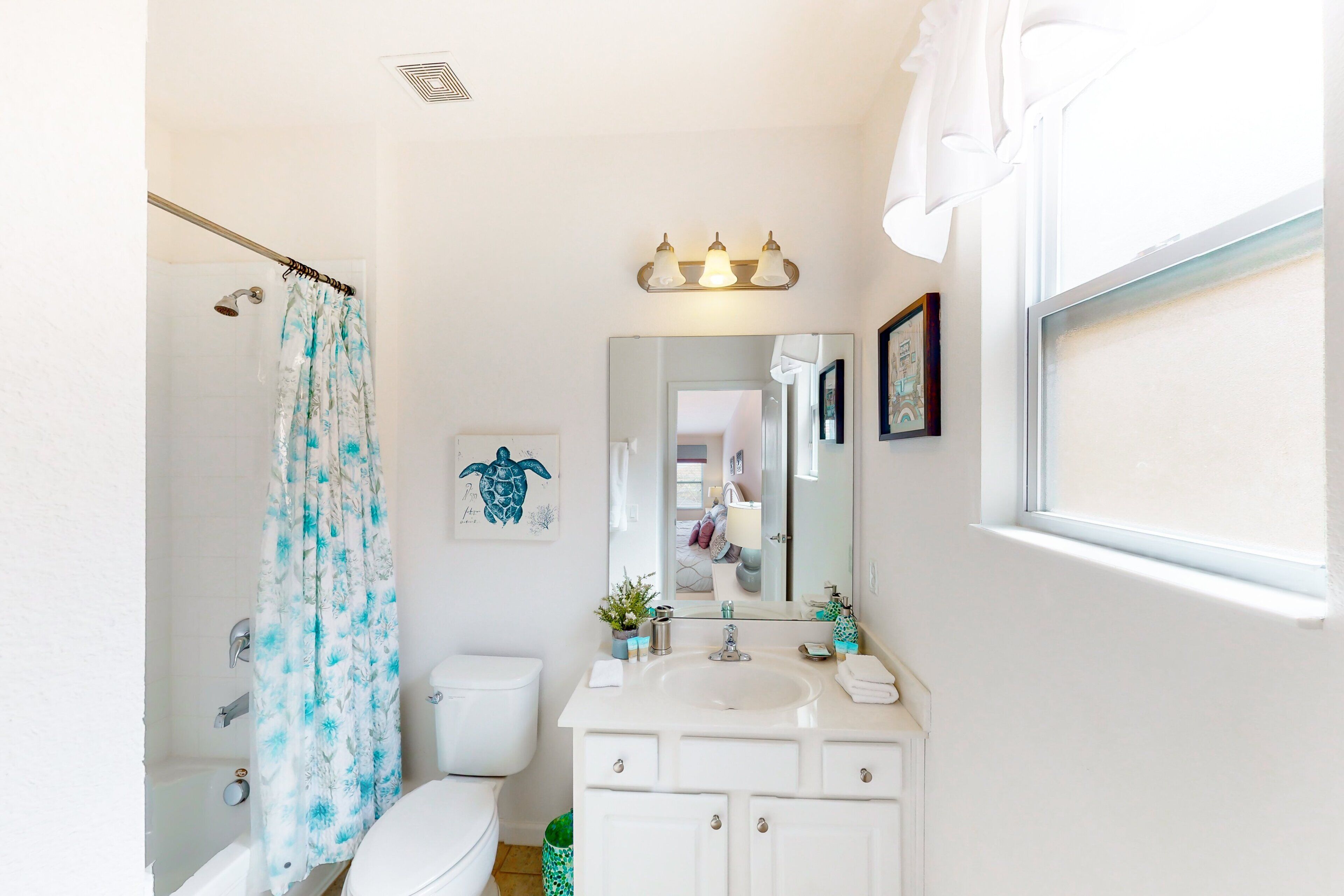 A bathroom with a shower, toilet, sink, and a mirror.