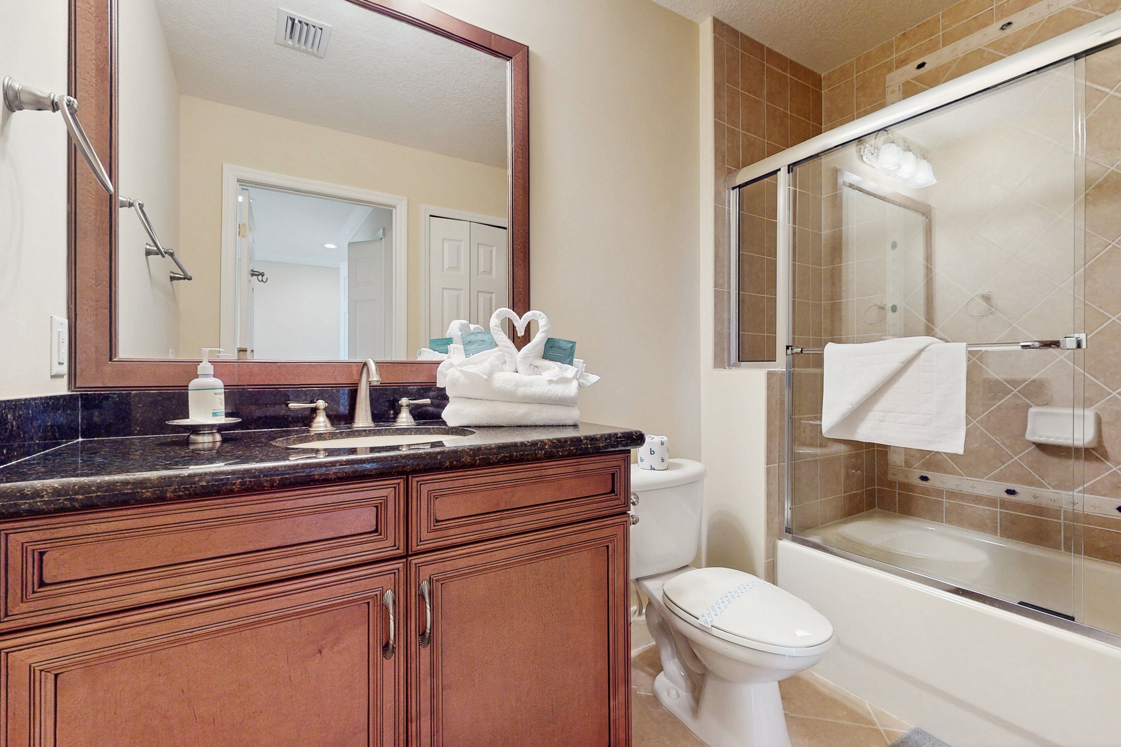 A bathroom with a vanity, a toilet, a shower enclosure, and a large mirror.