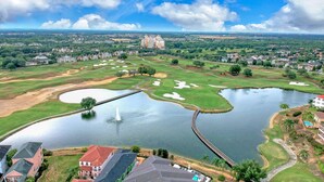 Ein Golfplatz mit Teich, Brücke und einem großen Gebäude im Hintergrund.