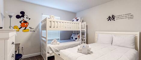 A child's bedroom with bunk beds, a Mickey Mouse wall decal, and a motivational quote.